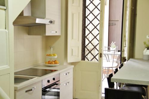 a kitchen with white cabinets and a table with a bowl of oranges at Dimora del sole in Catania