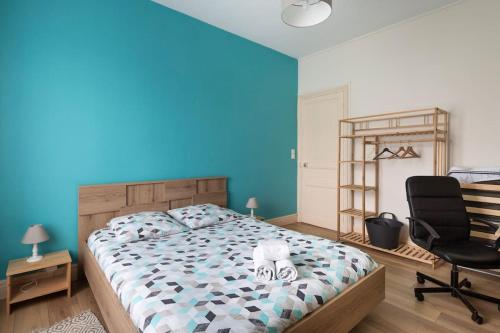 - une chambre avec un mur bleu, un lit et une chaise dans l'établissement Joli T3, gare & plages à proximité, à Saint-Malo