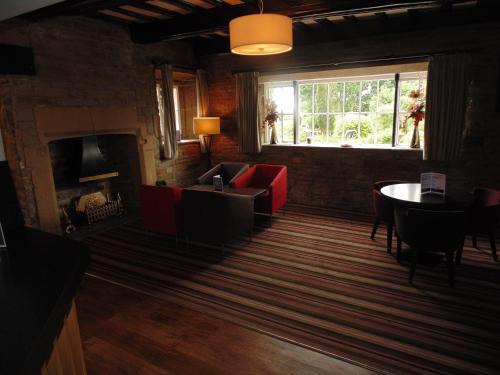 a living room with a fireplace and a table and chairs at Best Western Plus Lancashire Manor Hotel in Skelmersdale