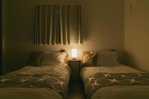 a bedroom with two beds with a lamp on it at Kourijima L'hotels in Nakijin