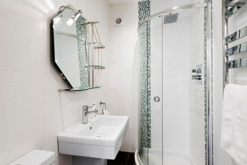 a white bathroom with a sink and a shower at 10 At The Beach, Torcross in Beesands
