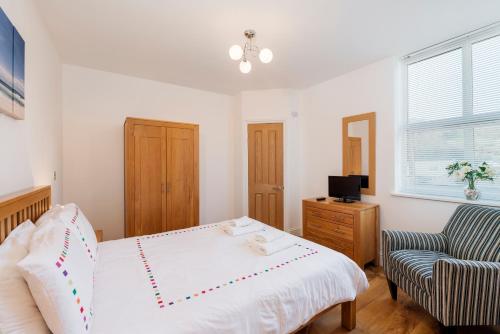 a bedroom with a white bed and a chair at 10 At The Beach, Torcross in Beesands