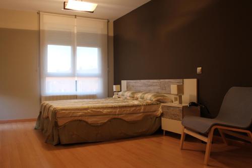 a bedroom with a bed and a chair and a window at Apartamento el Budha in Calahorra