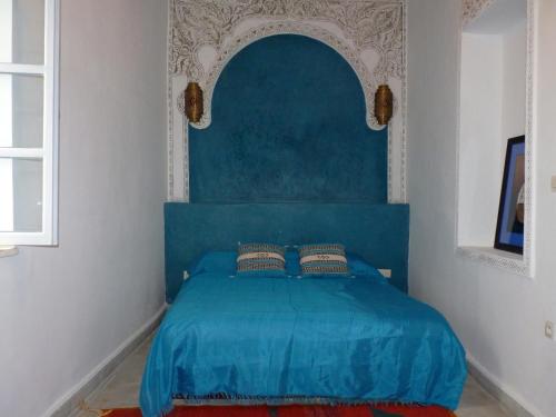 a blue bed with a blue headboard in a bedroom at Dar Mussarat in Essaouira
