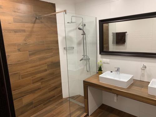 een badkamer met een wastafel en een douche met een spiegel bij Lili Motel in Sajószentpéter