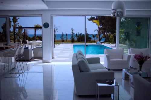 a living room with white furniture and a swimming pool at Katerina House in Perivolia