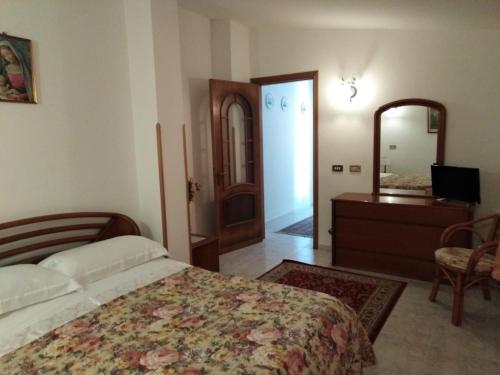 una camera con letto, cassettiera e specchio di Casa Natura sotto il Castello a Castelbuono