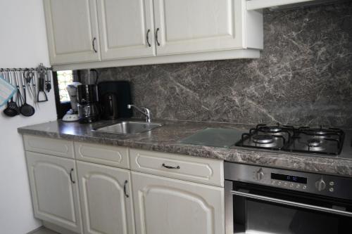 a kitchen with white cabinets and a stove and a sink at Klepperstee Esdoorn 3 in Ouddorp