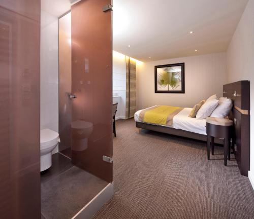 a bedroom with a bed and a bathroom with a toilet at Logis Hotel Restaurant Muller in Niederbronn-les-Bains