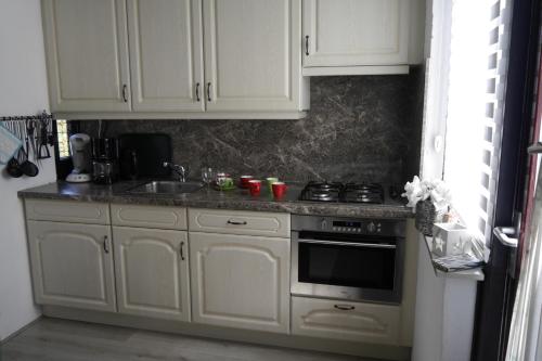a kitchen with white cabinets and a stove at Klepperstee Esdoorn 3 in Ouddorp