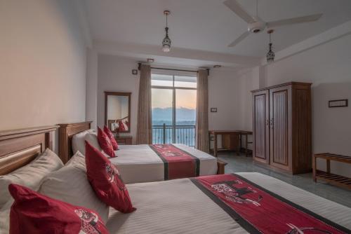 a hotel room with two beds and a balcony at Beauty Hills in Kandy