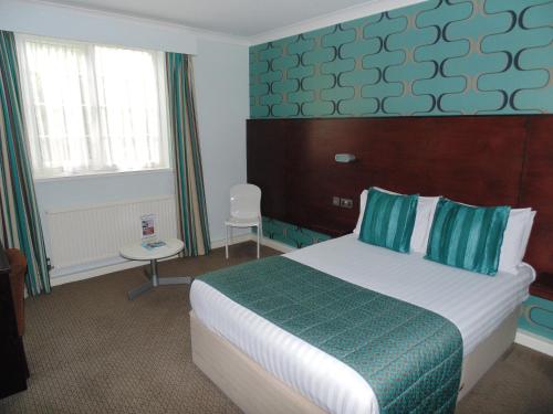 a hotel room with a bed with blue and green sheets at Best Western Plus Lancashire Manor Hotel in Skelmersdale