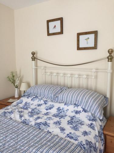 a bed with a blue and white comforter on it at QUILLET COTTAGE, 2 GLENTOWAN ROAD in St Austell