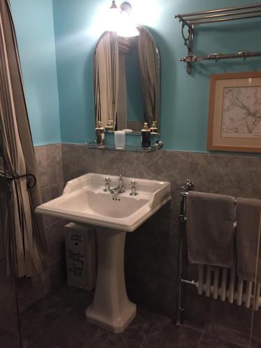 a bathroom with a sink and a mirror at QUILLET COTTAGE, 2 GLENTOWAN ROAD in St Austell