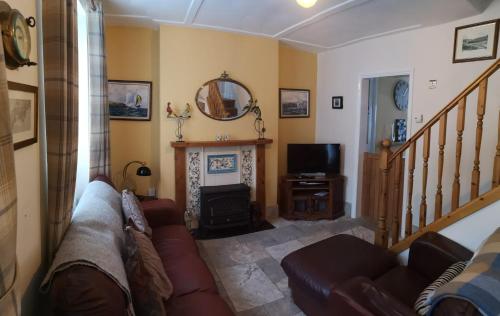 uma sala de estar com um sofá e uma lareira em QUILLET COTTAGE, 2 GLENTOWAN ROAD em St Austell