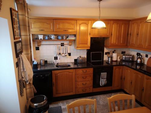 a kitchen with wooden cabinets and black appliances at QUILLET COTTAGE, 2 GLENTOWAN ROAD in St Austell