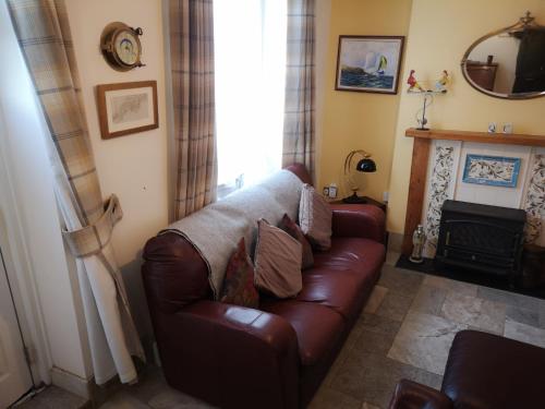 uma sala de estar com um sofá de couro castanho e uma lareira em QUILLET COTTAGE, 2 GLENTOWAN ROAD em St Austell