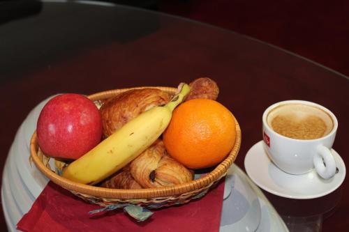 a basket of fruit with an apple orange and a cup of coffee at Hotel Regina Montmartre in Paris