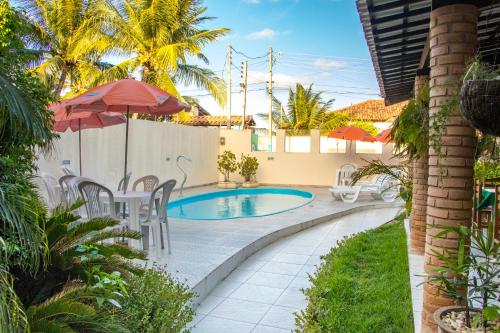 拉巴拉德納聖安東尼奧的住宿－Pousada Ilha Mar，后院的游泳池,配有椅子和遮阳伞