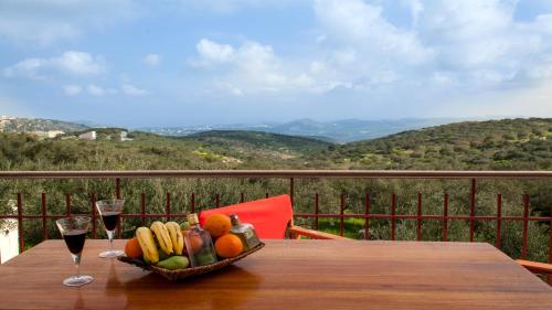 a basket of fruit on a table with two glasses of wine at Fοivos and Athina Villas in Archanes