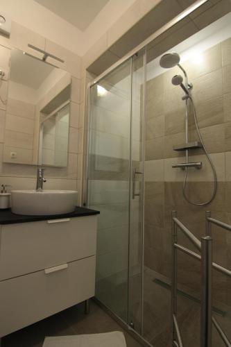een badkamer met een glazen douche en een wastafel bij Apartmani GORDANA in Mali Lošinj