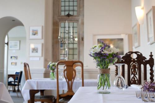 a dining room with a table with flowers on it at Amberley Inn in Stroud