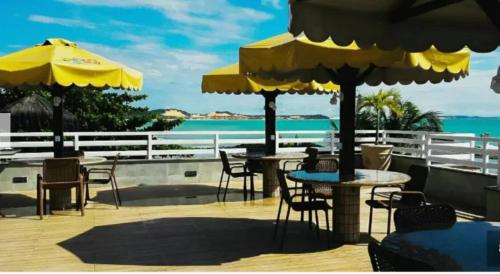 een terras met tafels, stoelen en parasols bij Sonia Flats Pipa's Bay - Flat 214 in Pipa