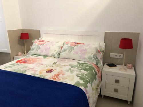 una camera da letto con un letto con copriletto floreale di Jano PuertaTierra a Cadice