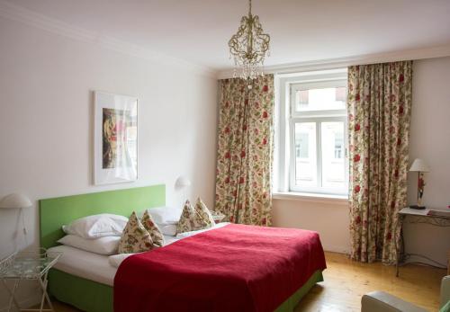 a bedroom with a bed with a red blanket and a window at das HOTEL in München in Munich