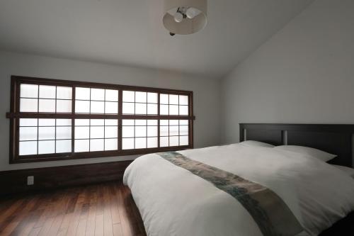 a bedroom with a large bed and two windows at 京都 六花庵 Kyoto Rokkaan in Kyoto