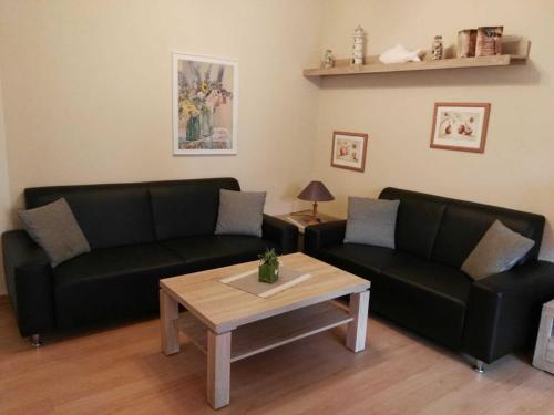 - un salon avec deux canapés noirs et une table basse dans l'établissement Ferienwohnung Boje 6 Schillig, à Schillig