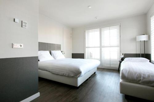 a bedroom with two beds and a window at Fletcher Hotel - Restaurant Nautisch Kwartier in Huizen