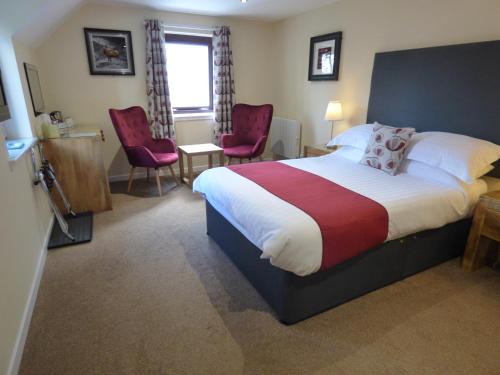 a hotel room with a bed and two chairs at The Brevins Guest House in Fort William