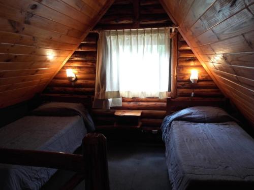 a bedroom with two beds in a log cabin at CABAÑAS LOS PATOS in Lago Puelo