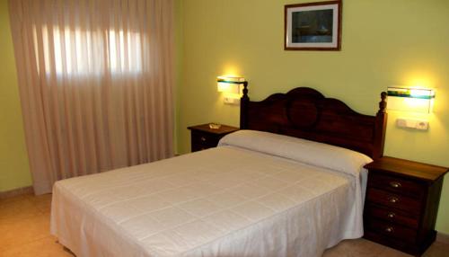 a bedroom with a white bed and two night stands at Alojamientos la Abuela in Rascafría