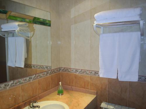 y baño con lavabo, espejo y toallas. en Alojamientos la Abuela en Rascafría