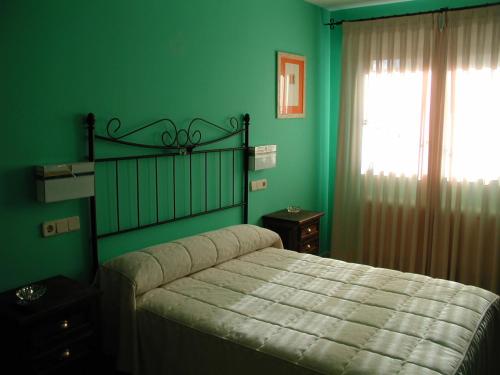 Un dormitorio con una cama con paredes verdes y una ventana en Alojamientos la Abuela en Rascafría