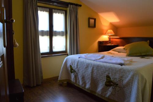 a bedroom with a bed with a white blanket and a window at Aldea de Con in Cangas de Onís