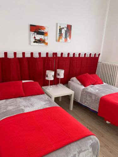 una camera con due letti con lenzuola rosse e un tavolo di Ostuni nuova casa vacanze a Ostuni