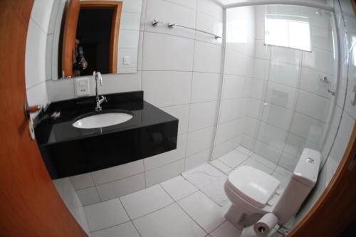 La salle de bains blanche est pourvue d'un lavabo et de toilettes. dans l'établissement Hotel Lorenzetti BR, à Guarapuava