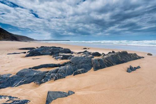 una playa de arena con grandes rocas en la arena en Casa Sol, en Carrapateira