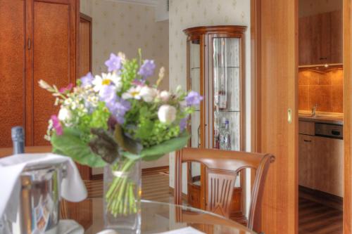 a vase of flowers sitting on a table at SEETELHOTEL Ahlbecker Hof das elegante Traditionshotel & ruhiger Rückzugsort an der Ostsee in Ahlbeck