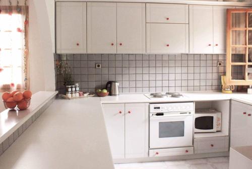 a white kitchen with white cabinets and a microwave at Koel Country House in Áno Almirí