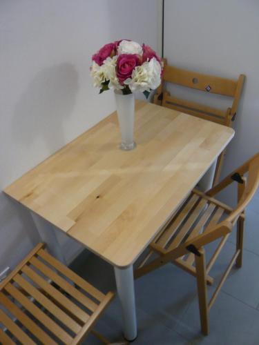 a vase of flowers on a wooden table with a chair at La casa di Balto, un nido per 2 in Castelnuovo Magra