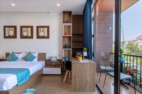 a bedroom with a bed and a desk and a balcony at Square Villa Hoi An in Hoi An