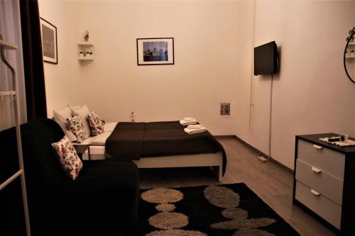 ブダペストにあるDuna Szecsi Apartmanのベッド1台とソファが備わる小さな客室です。