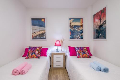 2 camas en una habitación con almohadas rosas y azules en Apartamento San Isidro, OZONO, en Granada