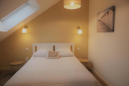 a bedroom with a white bed with two tables at La maison Virginie appartements climatisés de 1 à 5 pers cosy central parking gratuit linge fibre proximité port lac canal piscine in Montargis