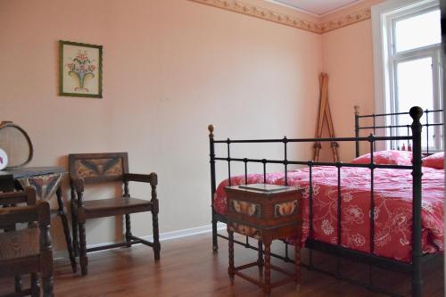 a bedroom with a bed and a chair and a window at Mooi! Gula Huset in Lidhult