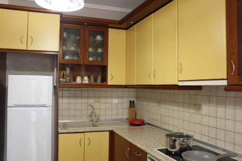 uma cozinha com armários amarelos e um frigorífico branco em SOUZANA ROOMS 1 em Nea Plagia